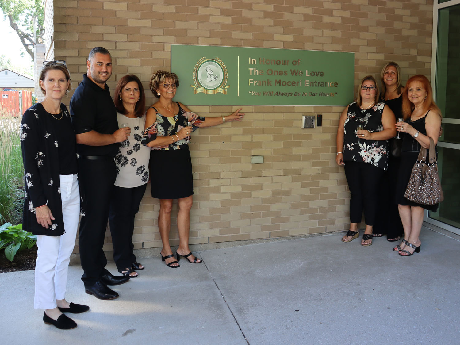 A group gathered around the Frank Moceri entrance plaque.